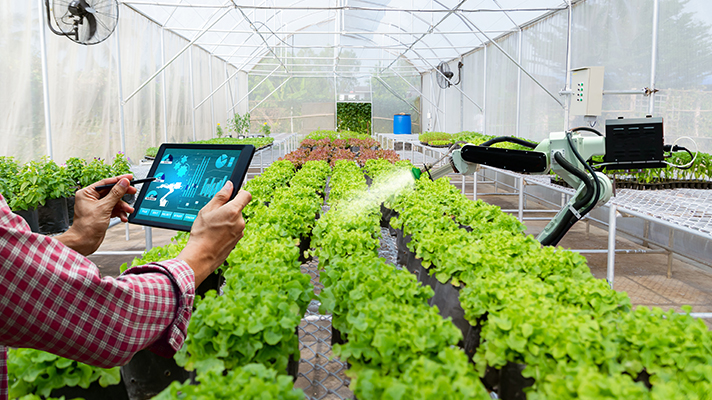 식물을 가꾸는 농업 로봇과 태블릿을 통해 이를 제어하는 사람의 모습