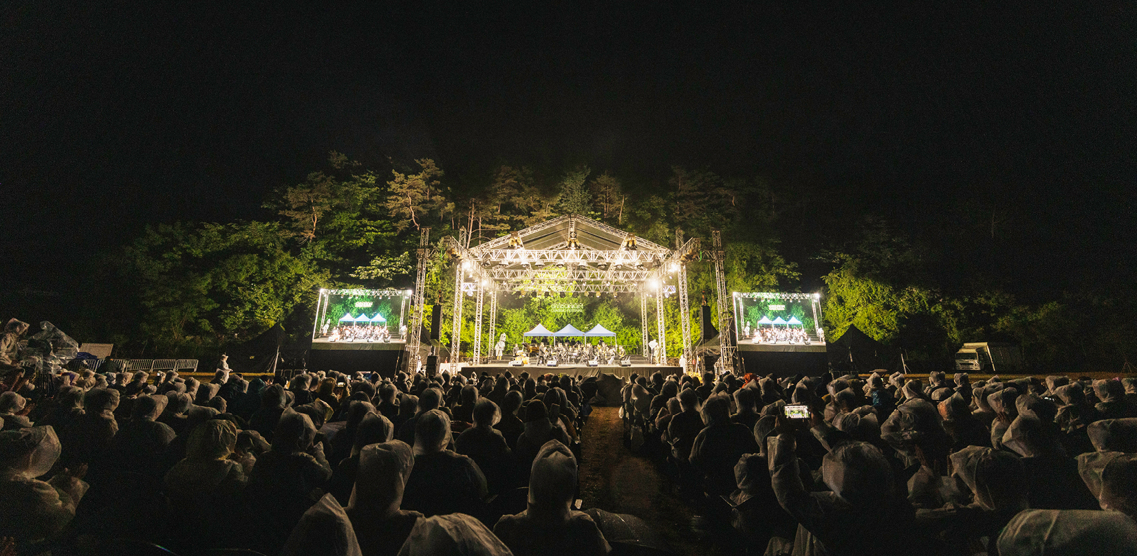 계촌 클래식 축제 2023 연주 장면으로 조명이 밝혀진 무대가 중앙에 있고, 이를즐기는 관객들의 뒷모습이 가득 담겨 있다.