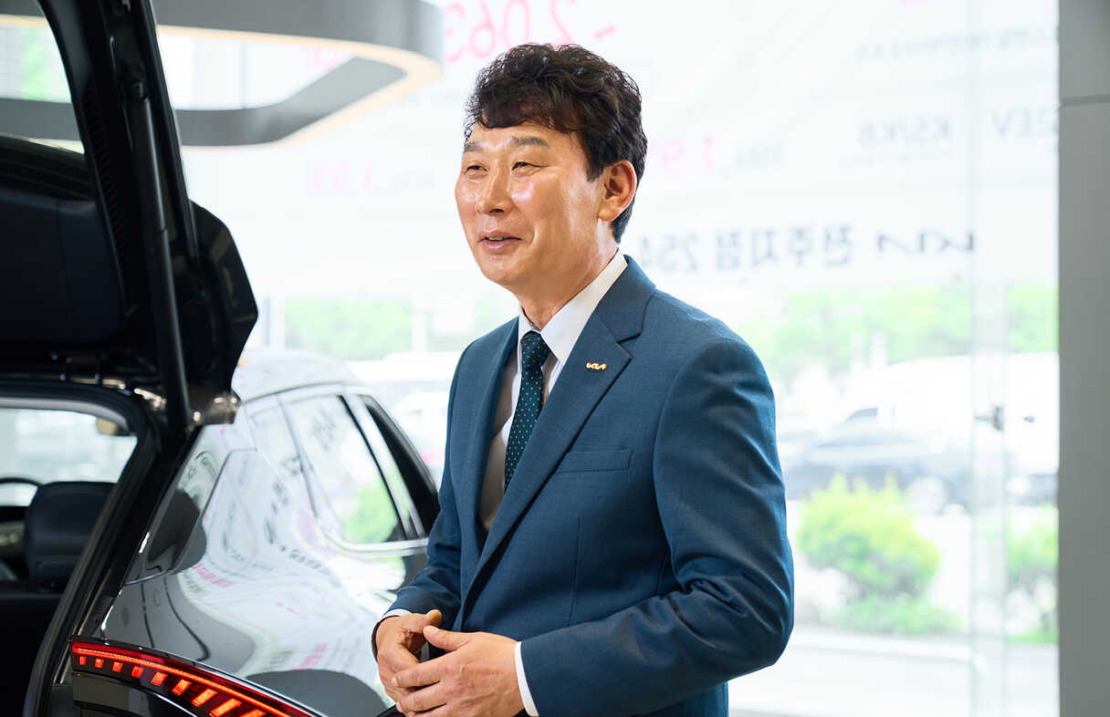 트렁크 열린 승용차 뒤에서 중년 신사가 웃는 모습