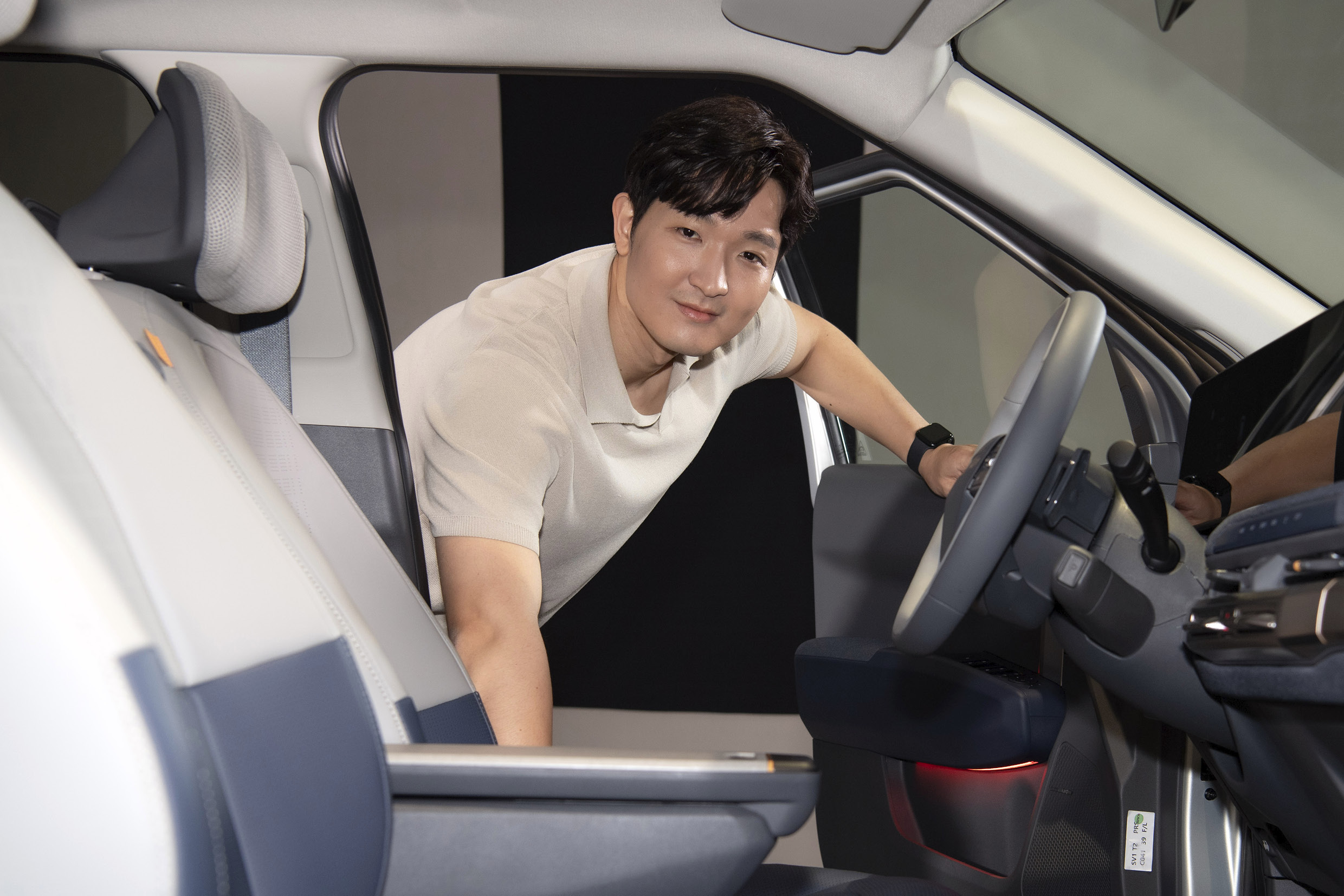 흰 옷 입은 남성이 운전석 문을 열고 상반신을 차 안으로 넣은 상태로 카메라를 응시하는 모습